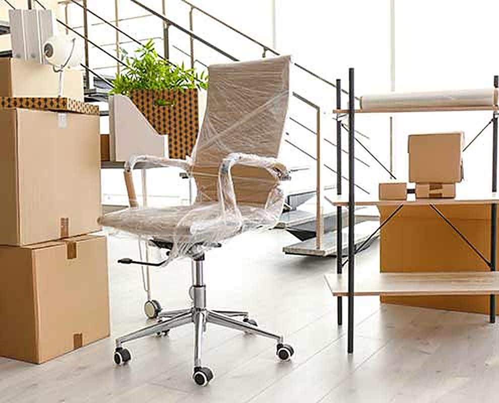 Büro mit verpacktem Bürostuhl und Umzugskartons
